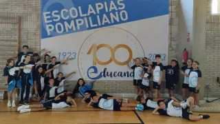 Algunos alumnos del colegio Pompiliano de Zaragoza, junto al cartel del centenario, en el pabellón deportivo del centro.