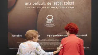 Dos mujeres se saludan junto a uno de los carteles de las películas que se proyectan en el 71 Festival Internacional de Cine de San Sebastián