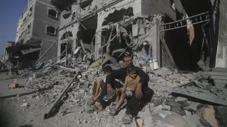 Palestinos sentados tras los ataques aéreos israelíes en el campo de refugiados de Rafah, en el sur de la Franja de Gaza.