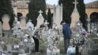 Dos personas colocan sus flores en una lápida del cementerio de Torrero, este sábado.
