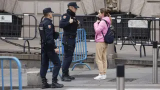 Dos agentes de la Policía nacional conversan con una mujer junto a unas vallas en los alrededores del Congreso de los Diputados en Madrid