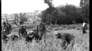 Campesinos y soldados siegan el cereal en Pancrudo, que aparece al fondo.