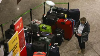 Una persona se dirige a reclamar su equipaje, en la terminal de Bilbao, ante varias maletas que no pudieron ser cargadas debido a la huelga de los trabajadores del servicio de asistencia en tierra o 'handling' de Iberia