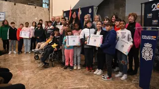 Foto de familia de las autoridades de Huesca con los escolares premiados en el concurso de dibujo de la Policía Nacional.