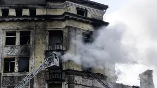 Bomberos ucranianos extinguen el fuego de un edificio destrozado por un misil ruso, este jueves en Kiev