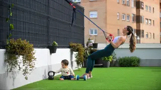 Lorena Garcia, árbitra de balonmano, durante un entrenamiento en la terraza de su casa. Al lado, el pequeño Martín, de 10 meses, juega con una kettlebell.