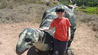 El pequeño Aris Romano junto a la maqueta del dinosaurio que se ha colocado en el entorno de Villanueva