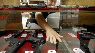 Un dependiente enseña las armas que vende en Wichita (Kansas), EE. UU.