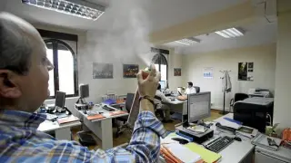 Un trabajador de los juzgados utiliza un ambientador para acabar con el mal olor de la oficina.