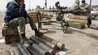 Rebeldes libios descansan sentados en municiones antes de salir hacia Ras Lanuf