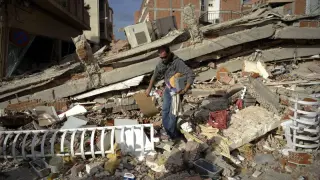 Un hombre busca entre los escombros de lo que era su casa
