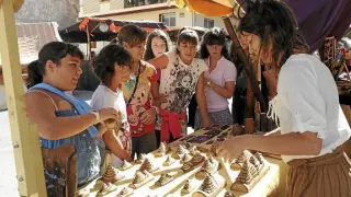 Un grupo de niños observa piezas artesanas de madera en una edición anterior de Artemon.
