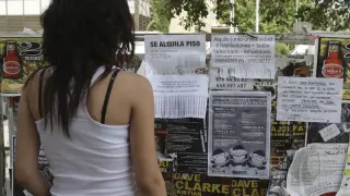 Una joven busca casa en los anuncios del campus.