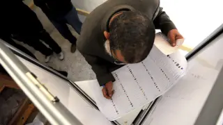 Un hombre cumplimenta su papeleta antes de ejercer su derecho al voto en El Cairo