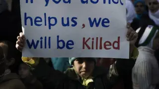 Un niño sirio enarbola un cartel pidiendo ayuda