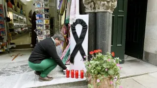 Una mujer pone una vela junto a un crespón por las víctimas del tren de Santiago.
