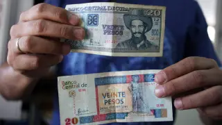 Un hombre muestra billetes cubanos de veinte pesos, uno de CUP (arriba) y otro de CUC (abajo)