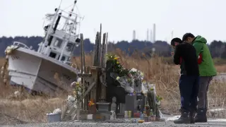 Dos personas rinden homenaje a las víctimas en un altar improvisado