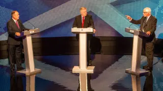 Salmond (izquierda) escucha a Darling (derecha) ante la mirada del moderador del debate