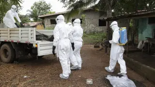 Varios trabajadores sanitarios liberianos desinfectan una casa en la que ha muerto una persona infectada de ébola tras retirar el cadáver.