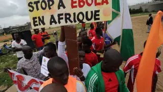 En un partido de fútbol, en Guinea, portan carteles contra el ébola.