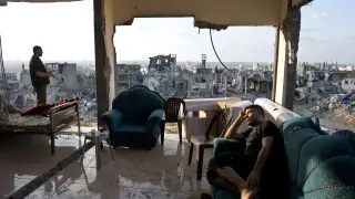 Dos gazatíes, en su casa, sin paredes y con las ruinas de fondo