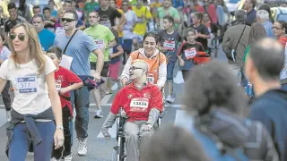 Una corredora empuja a un participante en silla de ruedas durante la pasada edición.