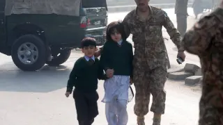 Un soldado escolta a dos niños evacuados de la escuela atacada