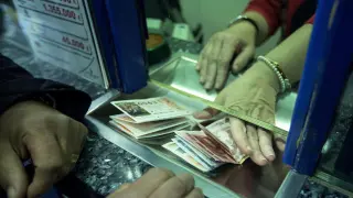 Un hombre compra varios décimos en una administración de lotería