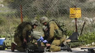 Un soldado isrelí herido recibe atención médica de varios compañeros después de que impactara un misil antitanques en su vehículo