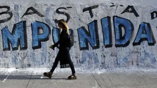 Una joven camina ante un muro en el que se pide el fin de la impunidad, en Buenos Aire