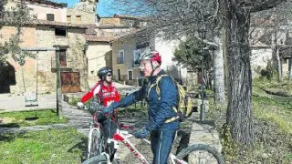 Dos ciclistas castellonenses, Vicente y Puri, reponen fuerzas durante un viaje por el Maestrazgo en la entrada al pueblo. El eslogan 'Miravete, el pueblo en el que nunca pasa nada' todavía es un referente para ellos.