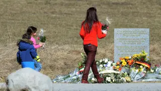 Una mujer y dos niños llevan flores a las víctimas