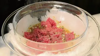 La carne y los ingredientes se mezclan en un bol bañado en agua y hielo.