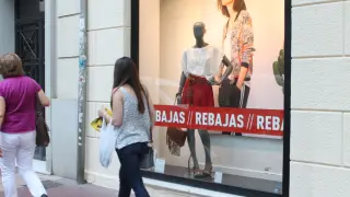 Una joven pasea junto al escaparate de un establecimiento con rebajas en Zaragoza.