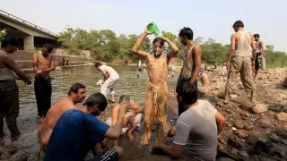 Un grupo de hombres se refresca en un río del sur de Pakistán