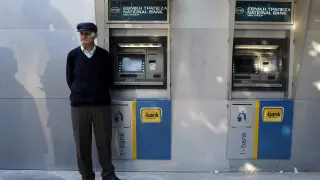 Un griego frente a cajeros del Banco Nacional de Grecia.