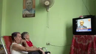 Unos cubanos escuchan en su casa a Obama por televisión.
