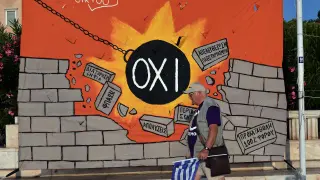 Un hombre pasa frente a una pared con un 'grafitti' anti austeridad