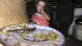 Una niña palestina muestra su plato de comida en la tienda de campaña familiar, en Susia.