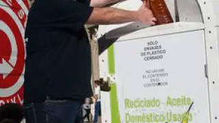 Un trabajador deposita una botella de aceite usado.