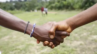 Ciudadanos de Liberia estrechan sus manos cerca de un campo escolar a las afueras de Monrovia (Liberia).