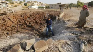 Un hombre de pie sobre un cráter causado según algunos medios por Rusia en Latamneh (Siria).