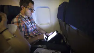 Un pasajero utilizando una tableta durante un viaje a bordo de un avión