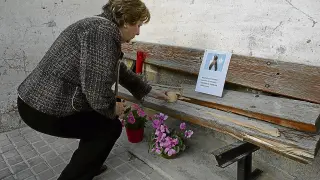 Una vecina de Peñalba pone una vela en el banco roto tras el suceso donde estaba sentada  la víctima cuando el turismo la arrolló y en el que ayer se dejaron flores y mensajes de condolencia.