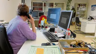 Una funcionaria atiende el teléfono ante dos ordenadores bloqueados por el virus.