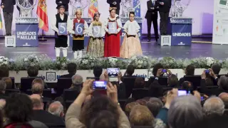 Niños de Huesca ataviados con trajes regionales muestran el número premiado ayer.