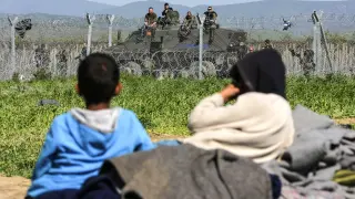 Unos niños descansan junto a la valla fronteriza en un campo de refugiados.