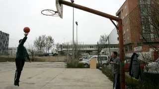 Dos jóvenes juegan a baloncesto en un potrero de Zaragoza