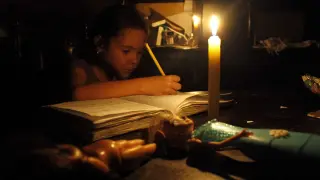 Una niña hace sus deberes con una vela encendida a causa de un corte de electricidad en San Cristóbal, en el estado de Tachira.